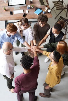 pexels-photo-3184423-3184423 A diverse group of professionals joins hands in a team-building exercise indoors.